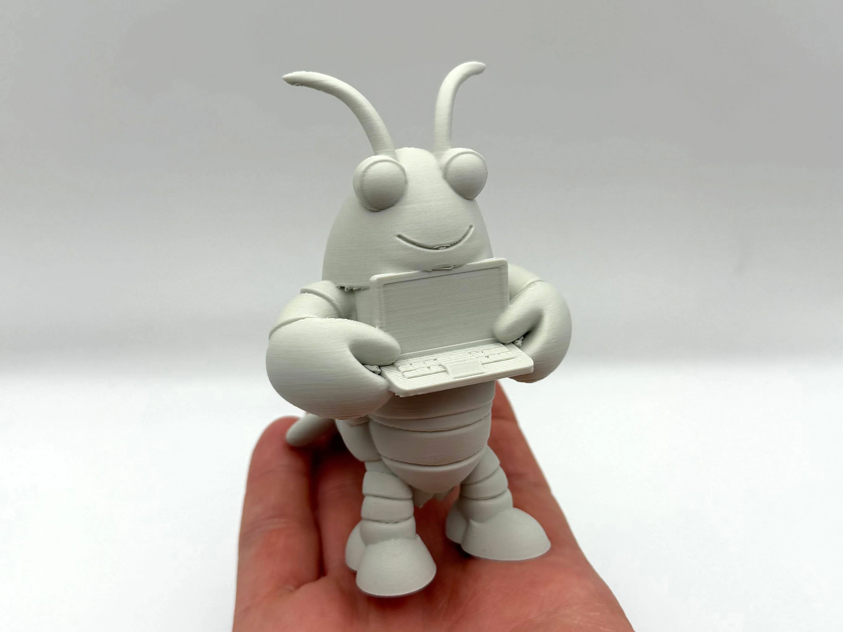 Large physical Molty mascot model holding a tiny computer