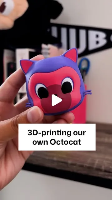 A hand holding a colorful 3D-printed Octocat