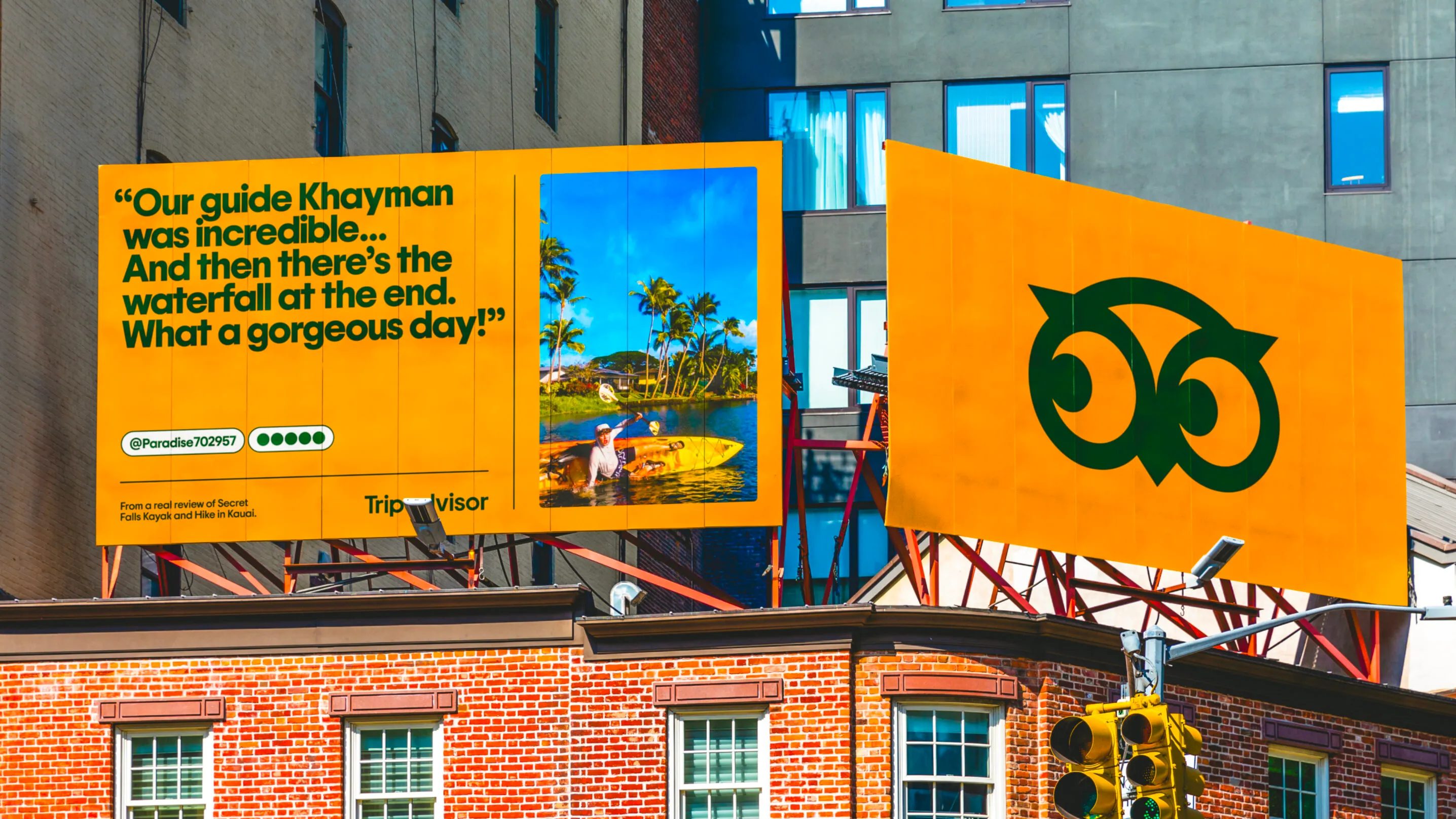 A giant Ollie owl face on a bright yellow Tripadvisor city billboard