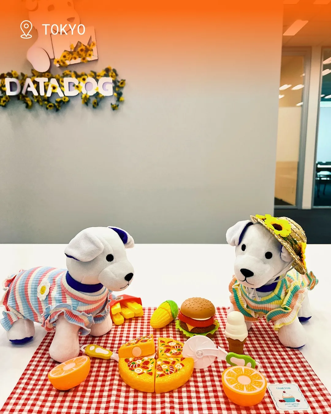 Two Datadog Bits plush mascots having a toy picnic in the Tokyo office